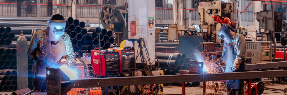 Metal fabrication workers welding in industrial manufacturing unit