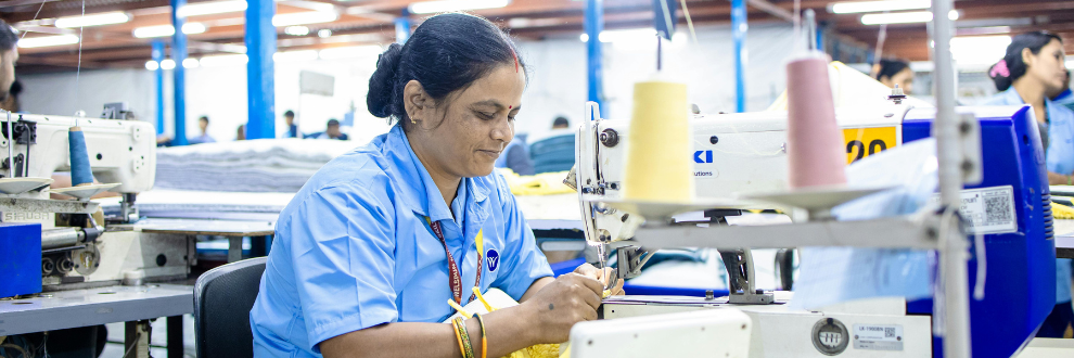 Garment manufacturing worker using industrial sewing machine in factory